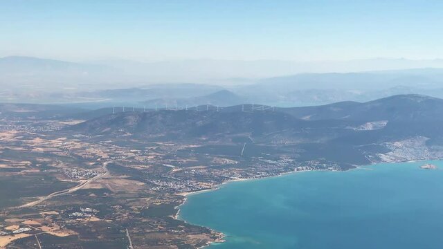 Large wind turbines with blades on the mountain. Aerial view drom airplane window. Wind power turbines generating clean renewable energy. Windmill farm. Power generation by wind turbines