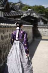 Woman in Korean traditional clothes standing at traditional Korean house