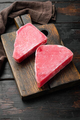Naklejka na ściany i meble Raw frozen tuna fish fillet, on wooden cutting board, on old dark wooden table background