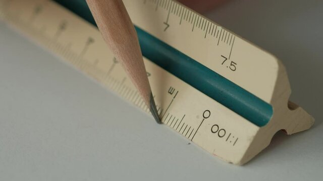 Close up, Male Hands using Triangle Scale Ruler with Wooden Pencil on White Paper, Drafting Tools.