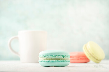 colorful macaroons and coffee on green background with copy space