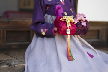 Woman in Korean traditional clothes holding traditional packages