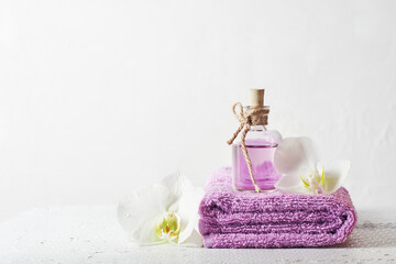 A bottle of lilac perfume and orchid flowers.