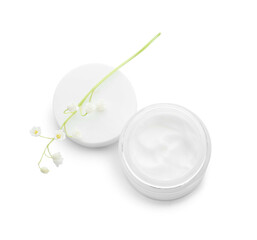 Jar of cream and lily-of-the-valley flowers on light background