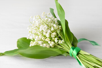 Obraz premium Beautiful lily-of-the-valley flowers on light wooden background, closeup