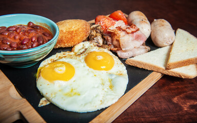 Fried eggs with bacon, sausages and beans