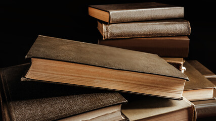 Photo of old fashioned stack of books on dark background.