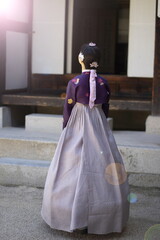 Fototapeta na wymiar Woman in Korean traditional clothes standing at traditional Korean house