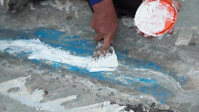 Workers are fixing cracks in the floor, spreading plaster using trowel, Repairing waterproofing deck flooring.	