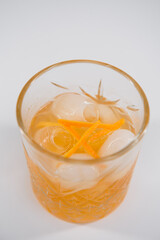 Glass of Boulevardier cocktail with big ice cube and orange zest, classic cocktail Boozy Boulevardier with Orange and Vermouth isolated on white background