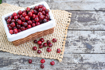 Red fresh Cherries in brown basket on wood table with beige wicker napkin. Ripe berries are delicious and contain healthy vitamins. Wonderful juice from fresh fruits. Garden full red tasty fruits