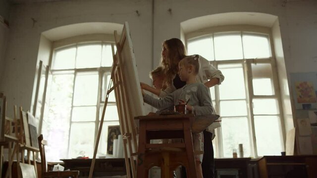 Contemporary family painting on easel. Creative children drawing indoors.