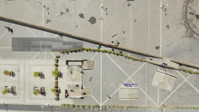 City square with skatepark zenith view in Palermo, people shadows walking . Drone from above camera flying over urban grey concrete scenery.