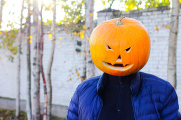 Halloween pumpkin head man in Jack lantern costume in autumn sunny forest