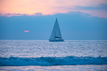 Fototapeta na wymiar Sailboat on the sea. Sailing boat floating on the blue ocean during sunrise with open main sail.