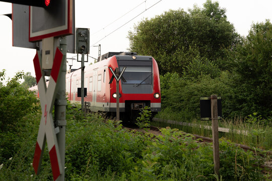 German Train incoming to crossroad with warning sign infront and nature in the background
