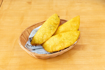 Wicker basket with ration of Colombian empanadas made with yellow corn flour stuffed with stewed beef