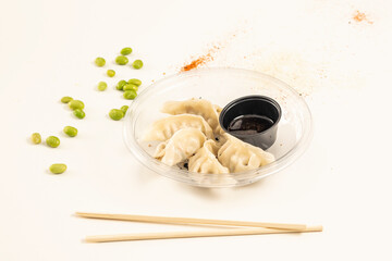 Japanese dumplings stuffed with prawns, gyozas, steamed and placed inside a transparent plate with chopsticks in the foreground