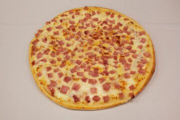 Super york ham pizza slice and spread over melted mozzarella cheese on a white cardboard background