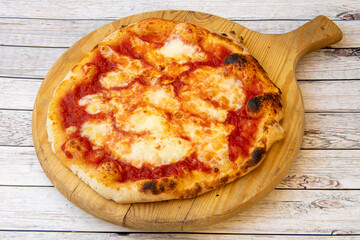 Pizza margarita in the purest Italian style with mozzarella cheese on wooden board