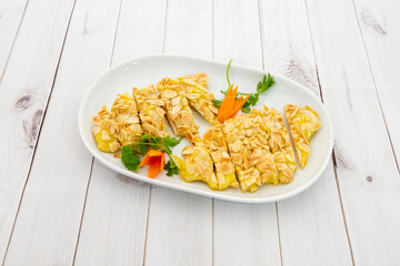 Chicken fillets battered with almond flakes accompanied by carrots and parsley inside a small white tray
