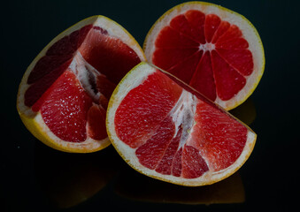 
Grapefruit, cut, three pieces, photo on a dark surface