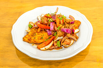 Tenderloin taco cooked with Peruvian recipe of vegetables and red onions sautéed with soy sauce on a white porcelain plate