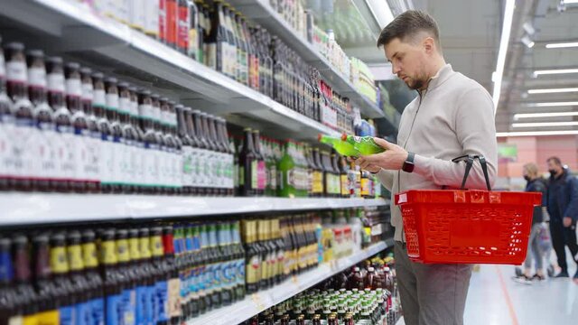 shopping in beer aisle in supermarket, adult man is taking two bottle