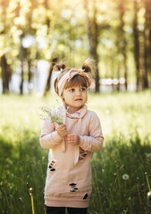 A little girl with a small bouquet of flowers in the park in the summer. Cute portrait. Vertical