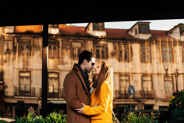 Obraz premium Cheerful couple in casual clothes smiling, kissing, walking together, spending time against the background of the building