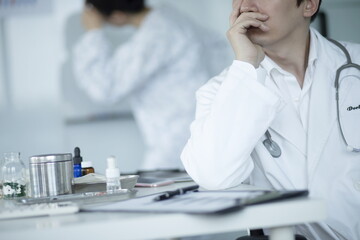 Pensive doctor sitting at desk in office