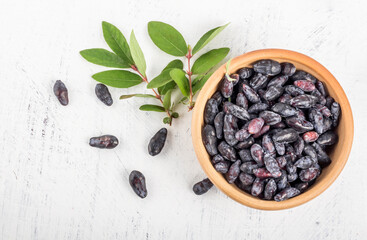Blue honeysuckle berries in a clay cup flat lay