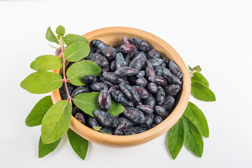 Blue honeysuckle berries in a clay cup on a white table top view