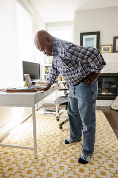 Mature Man With Sore Back Taking A Break From Working At Home