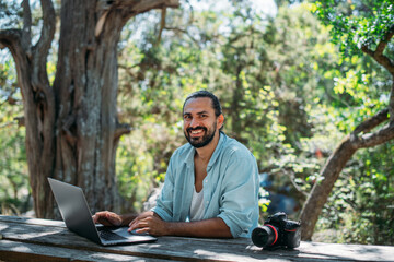 Male photographer working on a laptop outdoors in a camping