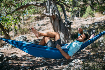 A man in a hammock on a hike in the mountains.