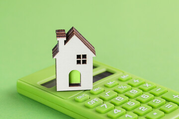 White house, green calculator on green background. Eco concept. Housing Purchase and insurance. Environmental Conservation - obrazy, fototapety, plakaty