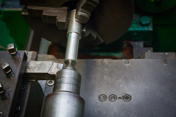 Mechanical processing of metal on a lathe, close-up. The steel bar is clamped in the lathe and the cutter is brought in. 