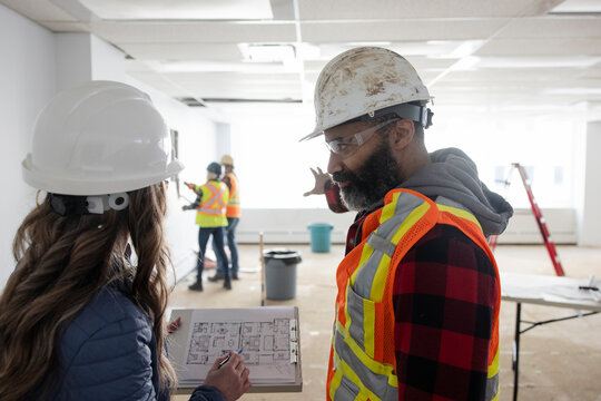 Site manager talking to construction foreman in empty office space