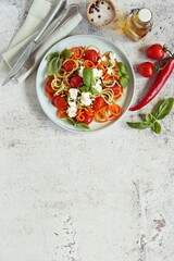 Warm salad from vegetable spaghetti , backed cherry tomatoes and goat cheese. Flat layot, copy space