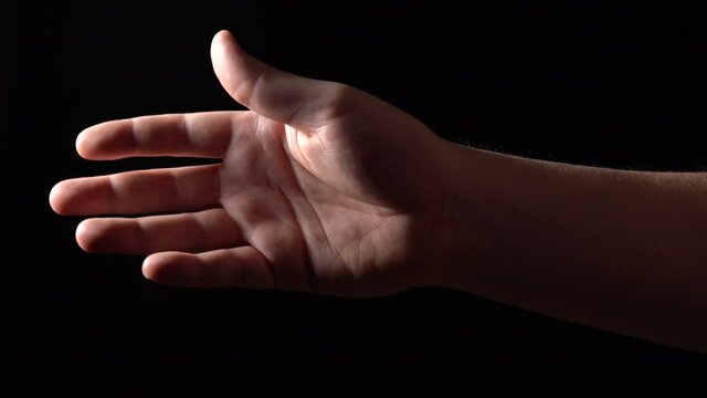 Hand Trying to Reach and Touch the Sky or Get Closer to the Light. Black background.