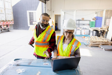 Warehouse managers talking at laptop at loading dock