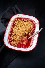 Modern style traditional American crumble cake with rhubarb and apple with backed topping served as close-up in a backing form