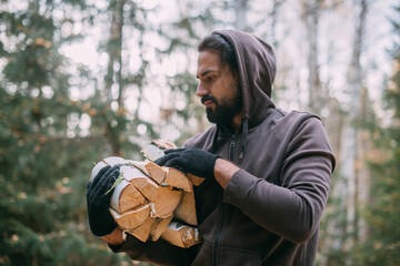 A man lumberjack holds firewood in his hands