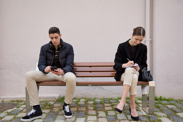 strangers sitting on a bench with distance - obrazy, fototapety, plakaty