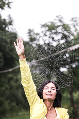 Young smiling woman touches the cobweb with her hand, daylight, frontal shooting, half-length portrait, smile