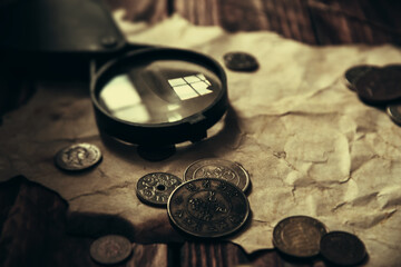 Vintage treasure map on table with coins and magnifying glass