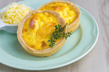 cheese lorraine quiches, some cheese and mint decorative elements, wooden base