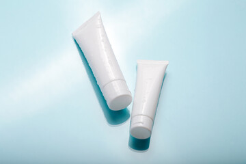 White cosmetic product in tubes on color background with water drops. Mock up skincare cosmetic...