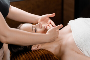 Facial massage close-up in spa center. Girl with perfect skin relaxing in massage room.